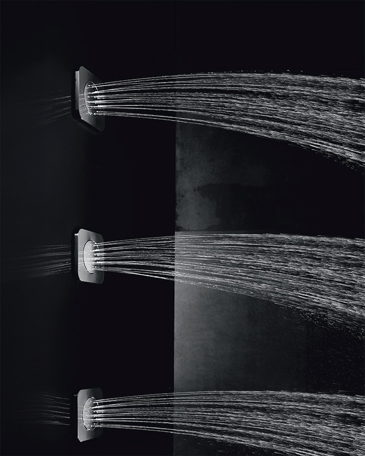 Three Soft Body Sprays delivering arced, directed water against a dark wall