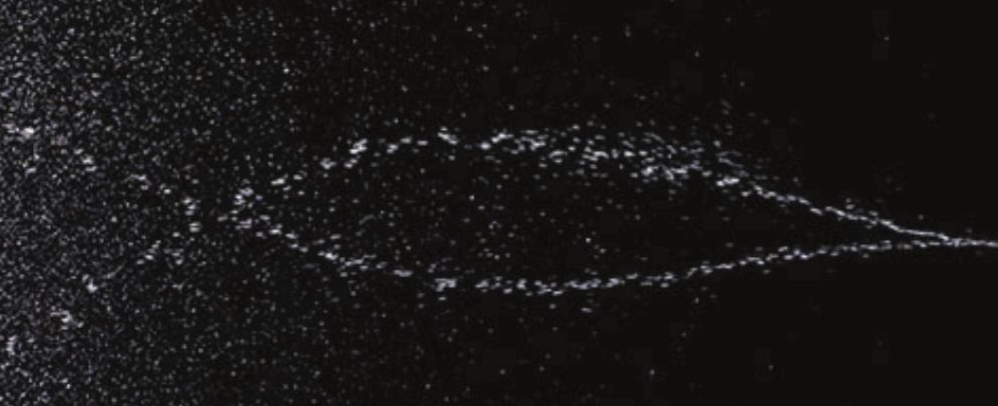 Spin Soft body spray emitting a fine, atomised cloud of droplets against a dark background